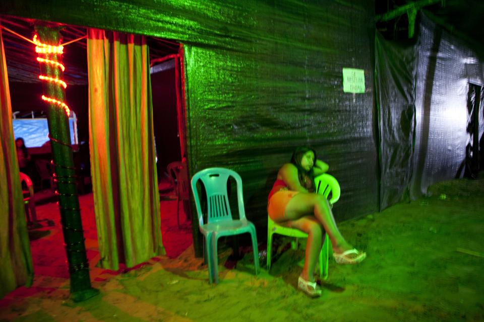 In this May 3, 2014 photo, a sex worker who is employed at an informal bar waits for customers in La Pampa in Peru's Madre de Dios region. Life is cheap in the mining camps. Deaths go unrecorded and the mercury miners use to bind gold flecks compounds the risks. Tons of the toxic metal have been dumped into rivers, contaminating fish, humans and other animals and plants. (AP Photo/Rodrigo Abd)