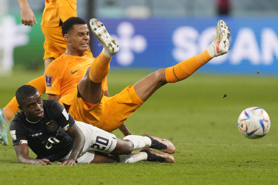 Cody Gakpo of the Netherlands, centre, and Ecuador's Jhegson Mendez, bottom, challenge for the ball during the World Cup group A soccer match between the Netherlands and Ecuador at the Khalifa International Stadium in Doha, Qatar, Friday, Nov. 25, 2022. (AP Photo/Darko Vojinovic)