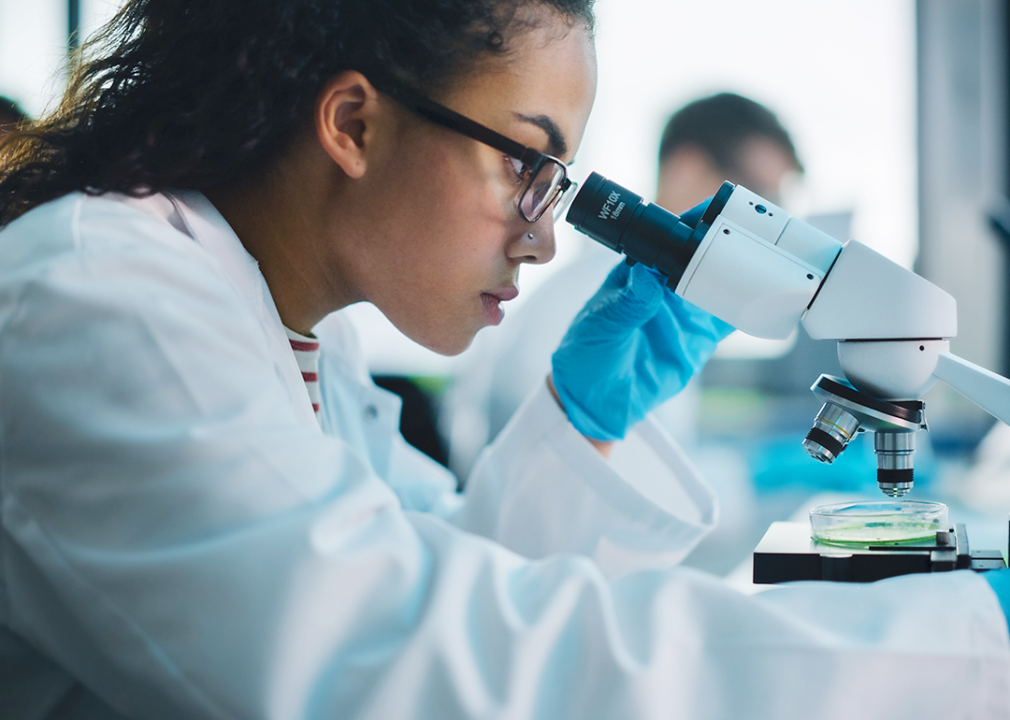 Woman working behind microscope in lab.