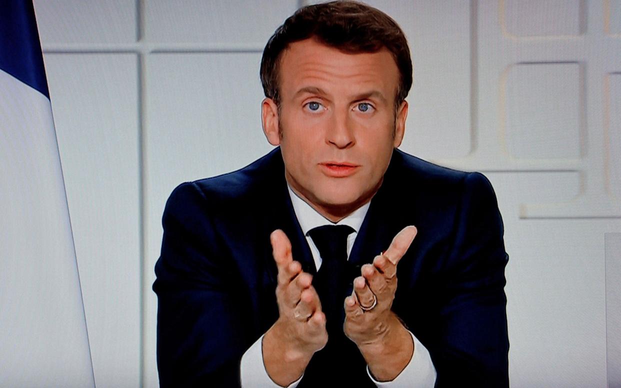 French President Emmanuel Macron is seen on a TV screen as he speaks during a televised address on the new Covid-19 restrictions  - AFP