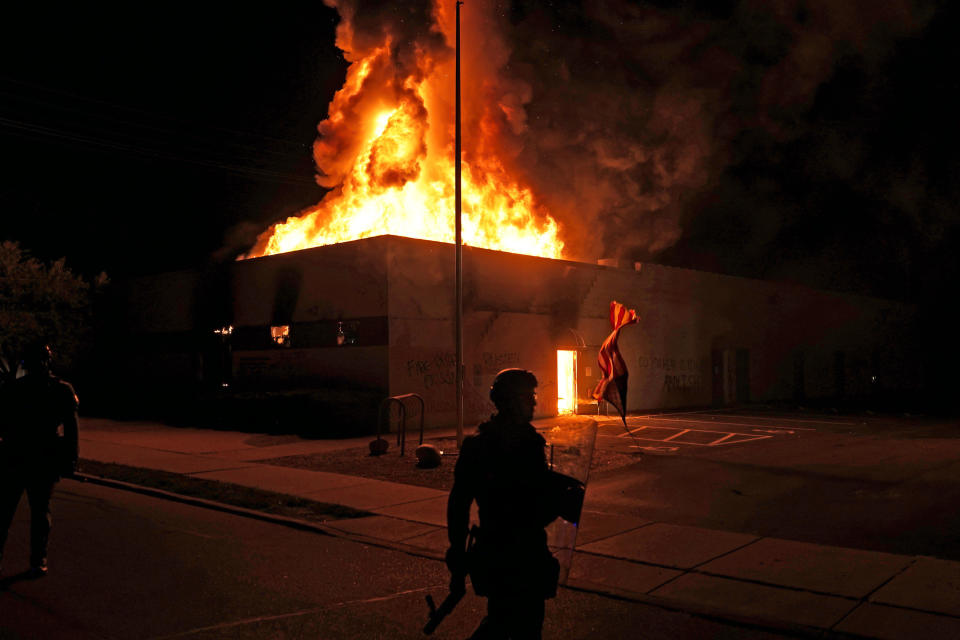 An American flag falls from its pole as police attempt to secure the area after protesters set fire to the department of corrections building, Aug. 24, 2020, in Kenosha, Wis. Protests have erupted following the police shooting of Jacob Blake a day earlier. The image was part of a series of photographs by The Associated Press that won the 2021 Pulitzer Prize for breaking news photography. (AP Photo/David Goldman)