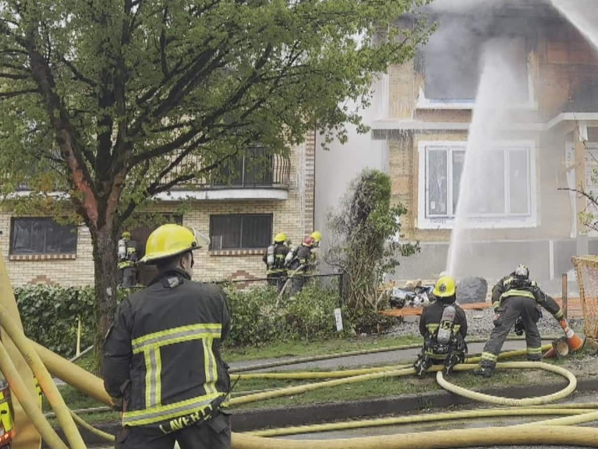 Firefighters extinguish a house fire in East Vancouver near Venables and Semlin streets on Friday, May 5, 2023. (Jessica Cheung/CBC News - image credit)