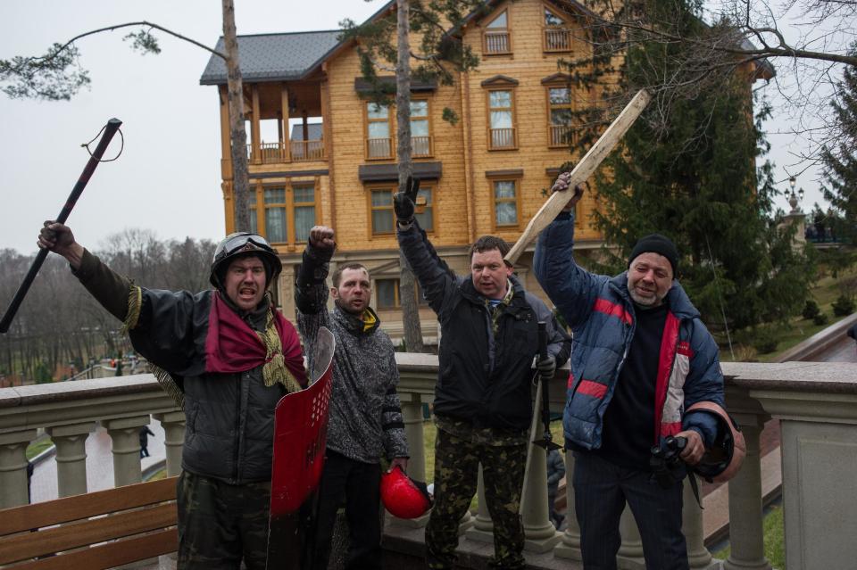 Protesters pose in front of the Ukrainian President Yanukovych's countryside residence in Mezhyhirya, Kiev's region, Ukraine, Saturday, Feb, 22, 2014. Ukrainian security and volunteers from among Independence Square protesters have joined forces to protect the presidential countryside retreat from vandalism and looting.(AP Photo/Andrew Lubimov)