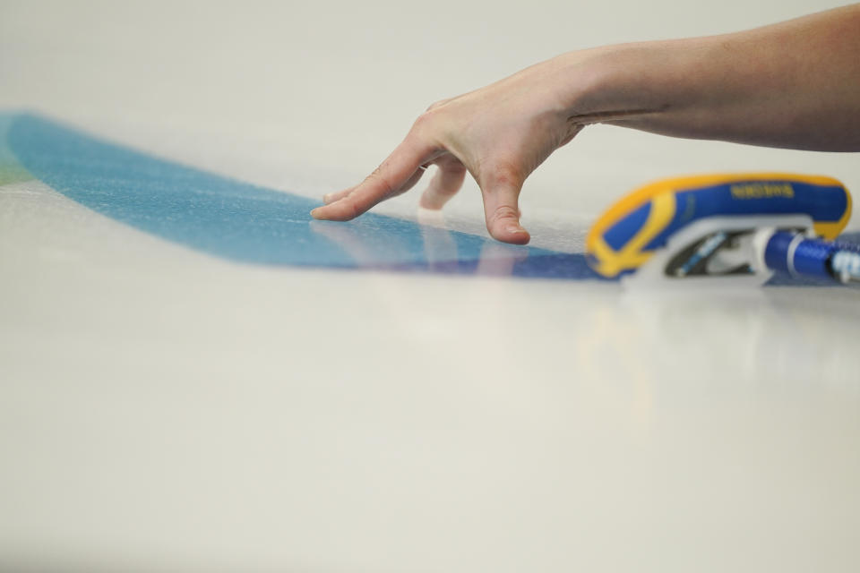Sweden's Sara Mcmanus slides her fingers on the ice after throwing a rock during a women's curling match against Canada at the Beijing Winter Olympics Saturday, Feb. 12, 2022, in Beijing. (AP Photo/Brynn Anderson)