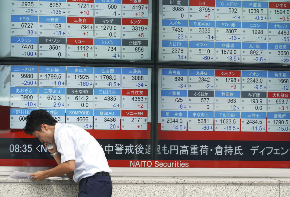 A woman walks past an electronic stock board showing Japan's Nikkei 225 index at a securities firm Tuesday, Aug. 21, 2018, in Tokyo. Asian shares are mixed amid doubts on the prospects for resolving the trade dispute between the U.S. and China. (AP Photo/Eugene Hoshiko)