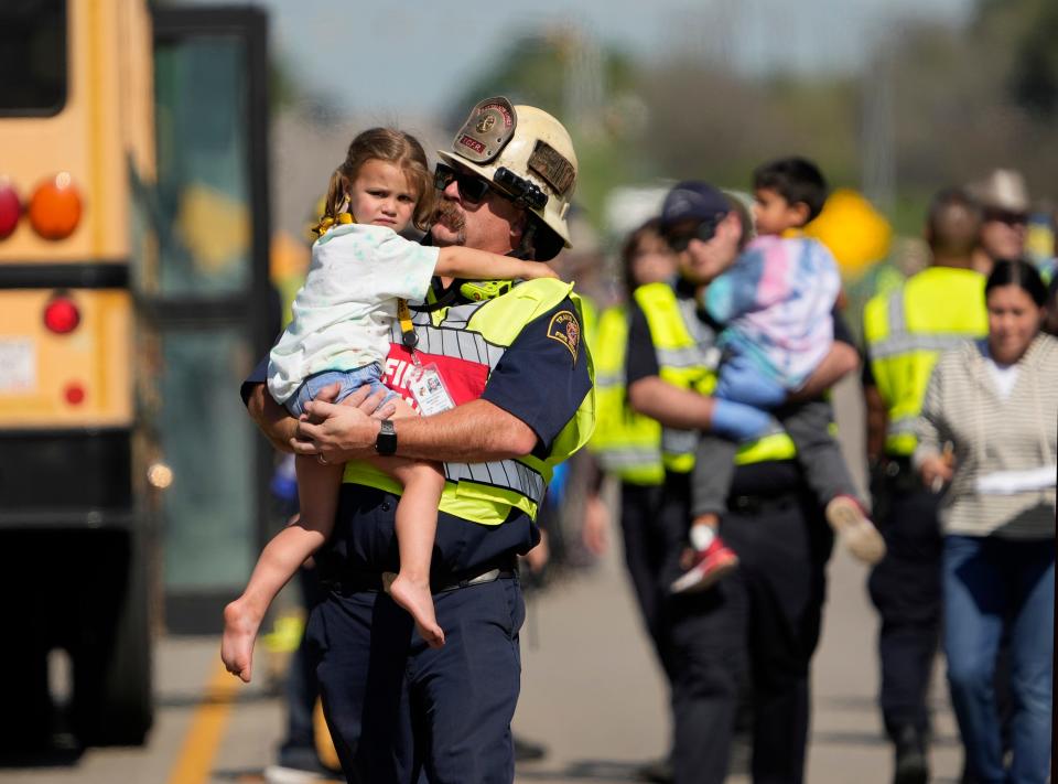 Jason Pack, jefe del batallón de rescate de bomberos del condado de Travis, consuela a una niña después de un accidente fatal que involucró un autobús escolar del distrito escolar de Hays en la autopista Texas 21 cerca de Caldwell Road el 22 de marzo.