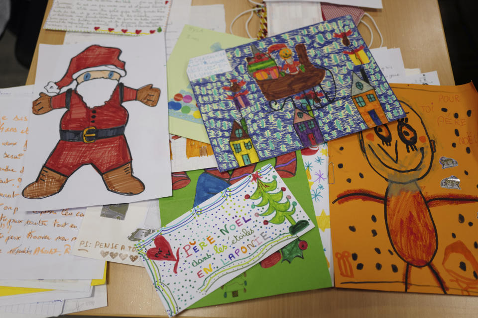 Envelopes addressed to "Pere Noel" - Father Christmas in French - decorated with love hearts, stickers and glitter, are displayed by postal workers in Libourne, southwest France, Monday, Nov. 23, 2020. Letters pouring by the tens of thousands into Santa's mailbox offer a glimpse into the worries and hopes of children awaiting a pandemic-hit Christmas. Along with usual pleas for toys and gadgets, kids are also mailing requests for vaccines, for visits from grandparents, for life to return to the way it was. The office estimates that one letter in three mentions the pandemic. (AP Photo/Francois Mori)