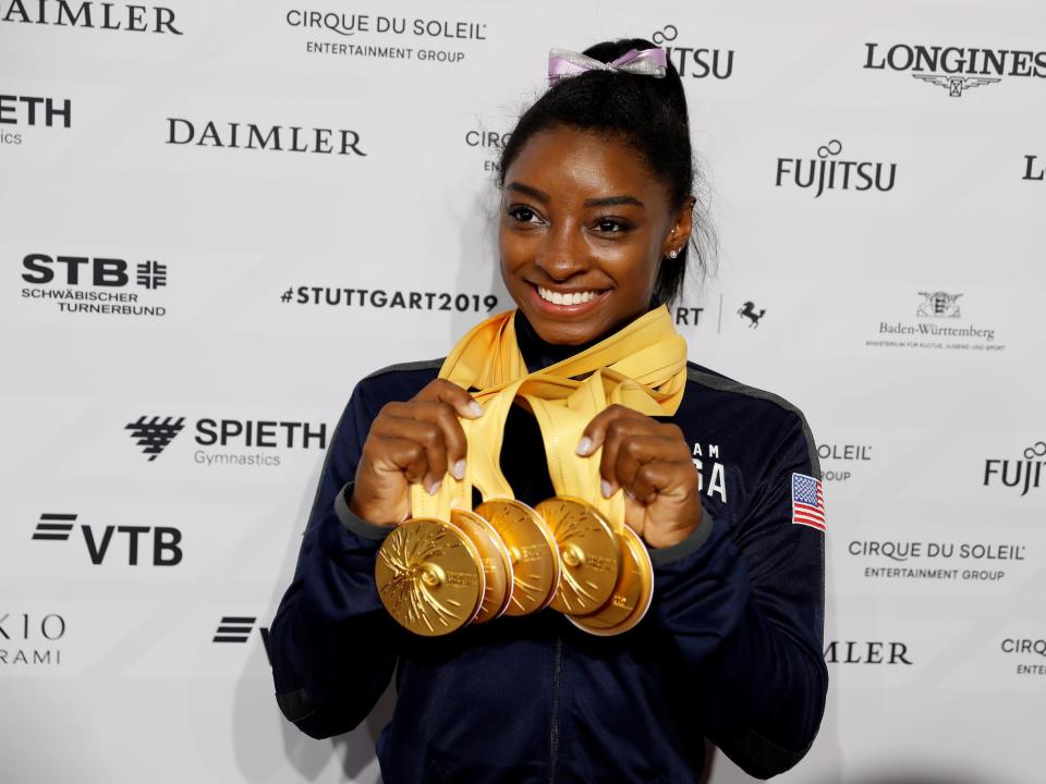 Simone Biles poses with five of her World Championship gold medals.