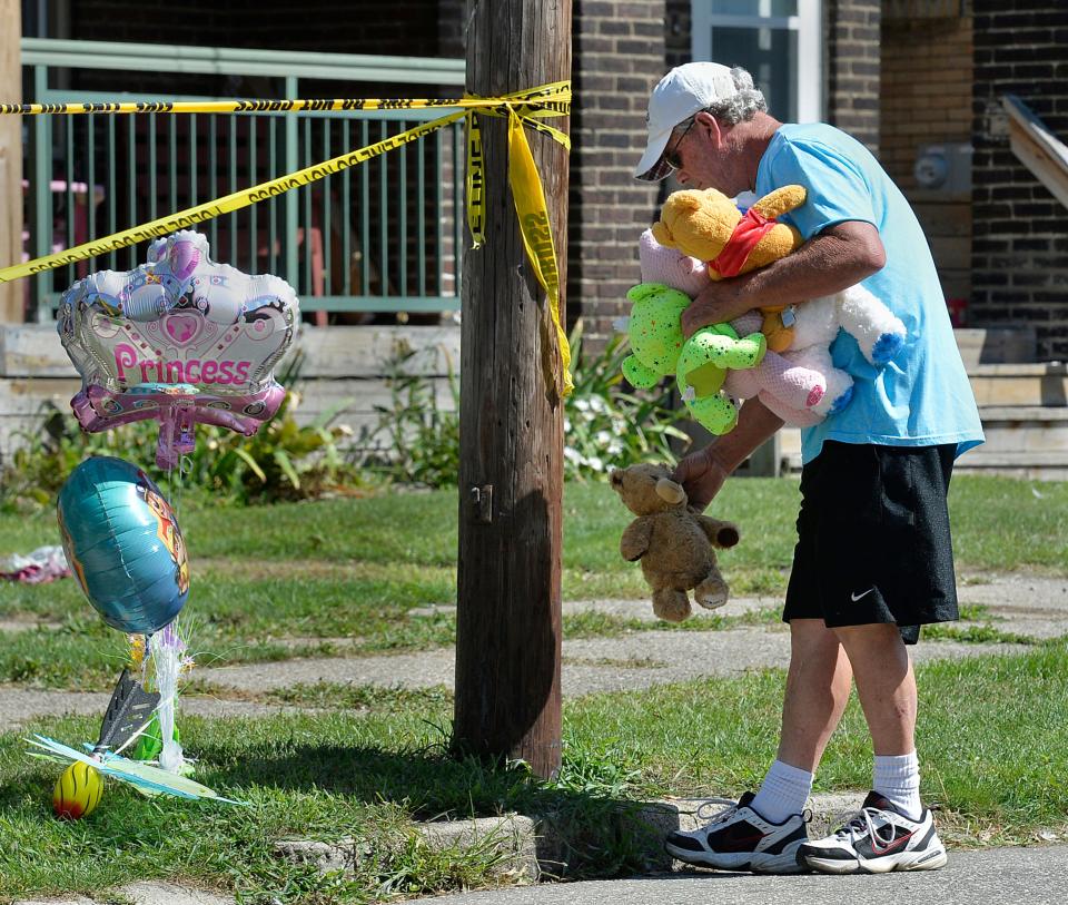 Paul Laughlin, 57, places stuffed animals on Sunday, Aug. 11, 2019 outside a home at 1248 West 11th St. in Erie, Pa., where multiple people died in an early-morning fire.   (Greg Wohlford/Erie Times-News via AP) ORG XMIT: PAERI102