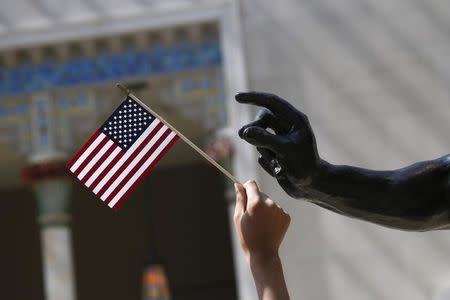 A girl holds a U.S. flag next to a sculpture after a naturalization ceremony at The Metropolitan Museum of Art in New York July 22, 2014. REUTERS/Shannon Stapleton/Files
