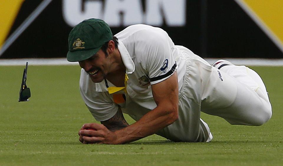 The sunglasses of Australia's Mitchell Johnson falls off as he dives to take a catch to dismiss England's Ian Bell during the fourth day of the second Ashes test cricket match at the Adelaide Oval December 8, 2013.