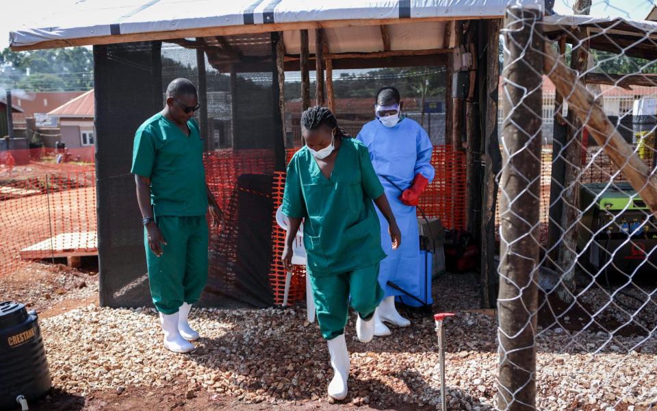 A medical attendant disinfects the rubber boots of a medical officer before leaving the Ebola isolation section of Mubende Regional Referral Hospital - AP Photo/Hajarah Nalwadda