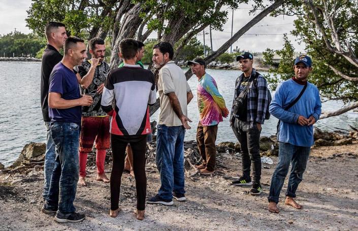 Members of two groups of Cuban migrants from Matanzas — one with 19 people, the other with 12 — stand in the sun on the side of U.S. 1 in the Middle Keys island of Duck Key Monday morning. By noon, they said they had been standing there waiting to be picked up by U.S. Border Patrol agents since arriving in two rustic vessels at 2:30 a.m. on Jan. 2, 2023.