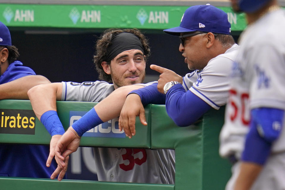 Los Angeles Dodgers manager Dave Roberts, right, talks with Cody Bellinger, left, in the dugout during a baseball game against the Pittsburgh Pirates in Pittsburgh, Thursday, June 10, 2021. (AP Photo/Gene J. Puskar)
