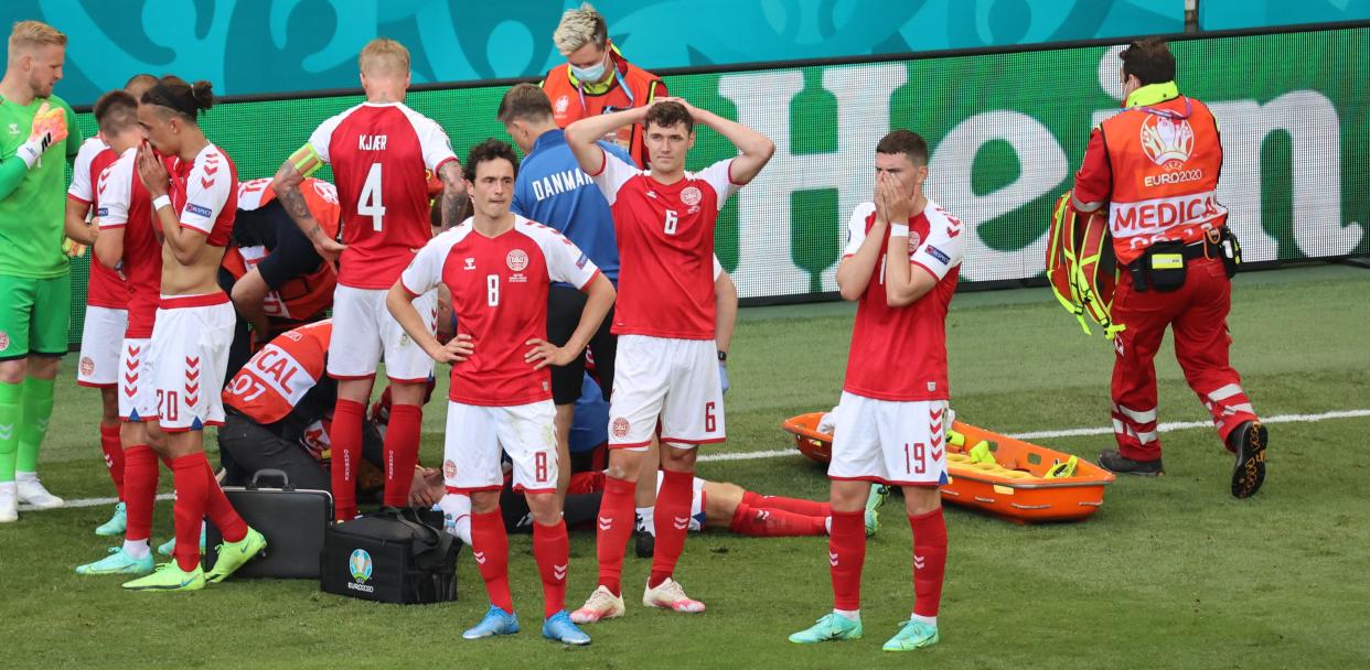 Denmark players react as paramedics attend to midfielder Christian Eriksen after he collapsed on the pitch during the during Saturday's Euro 2020 match against Finland. (Photo by Wolfgang Rattay/AFP via Getty Images)