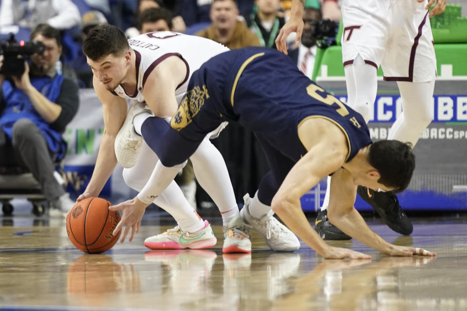 Virginia Tech guard Hunter Cattoor (0) gets his hands on the ball as Notre Dame guard Cormac Ryan (5) defends during the first half of an NCAA college basketball game at the Atlantic Coast Conference men's tournament in Greensboro, N.C., Tuesday, March 7, 2023. (AP Photo/Chuck Burton)