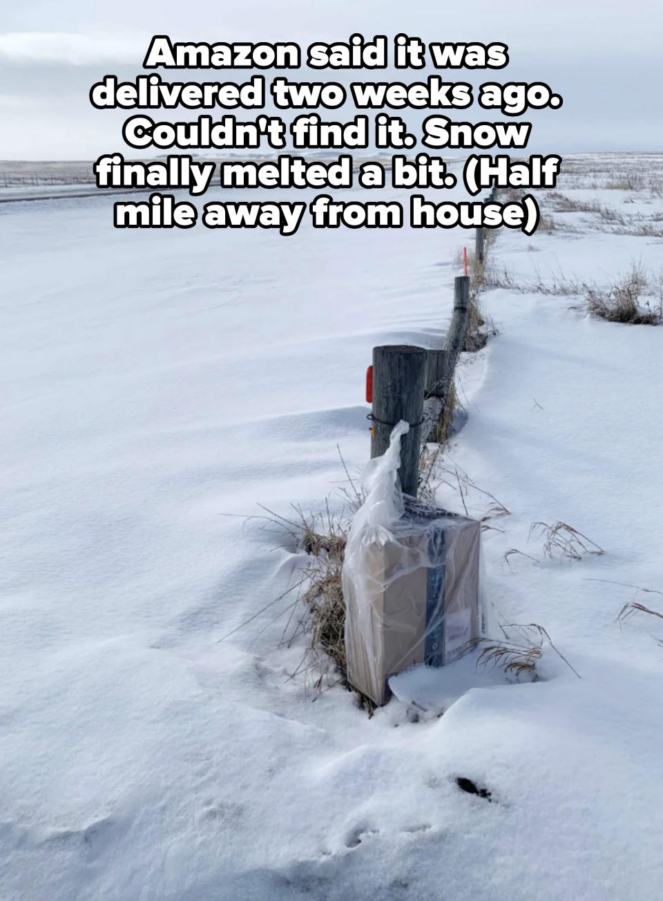 A snow-covered landscape with a fence and a package stuck at its base