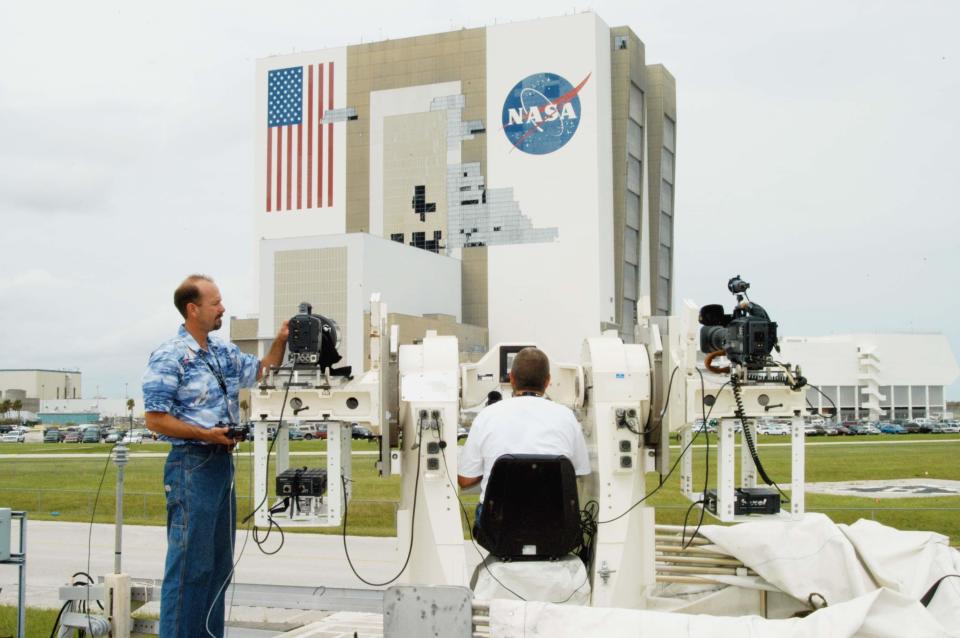 Sept. 14, 2004: A Kennedy Space Center videographer is seen in front of the Vehicle Assembly Building, which sustained damage from the historic 2004 hurricane season. The VAB lost 820 panels or more than 52,000 square feet of its surface.