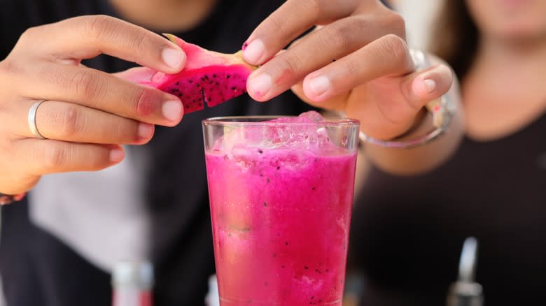 Hands garnishing a dragon fruit cocktail