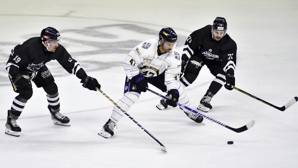 Nottingham Panthers Jordan Kelsall, centre, battles with Manchester Storm's Tommy Parran, left, and Manchester Storm's Callum Fryer during the Ice Hockey Adam Johnson memorial game between Nottingham Panthers and Manchester Storm at the Motorpoint Arena, Nottingham, England, Saturday, Nov. 18, 2023. The memorial game is held three weeks after Adam Johnson, 29, suffered a fatal cut to his neck during a game against Sheffield Steelers on Saturday, October 28. (AP Photo/Rui Vieira)