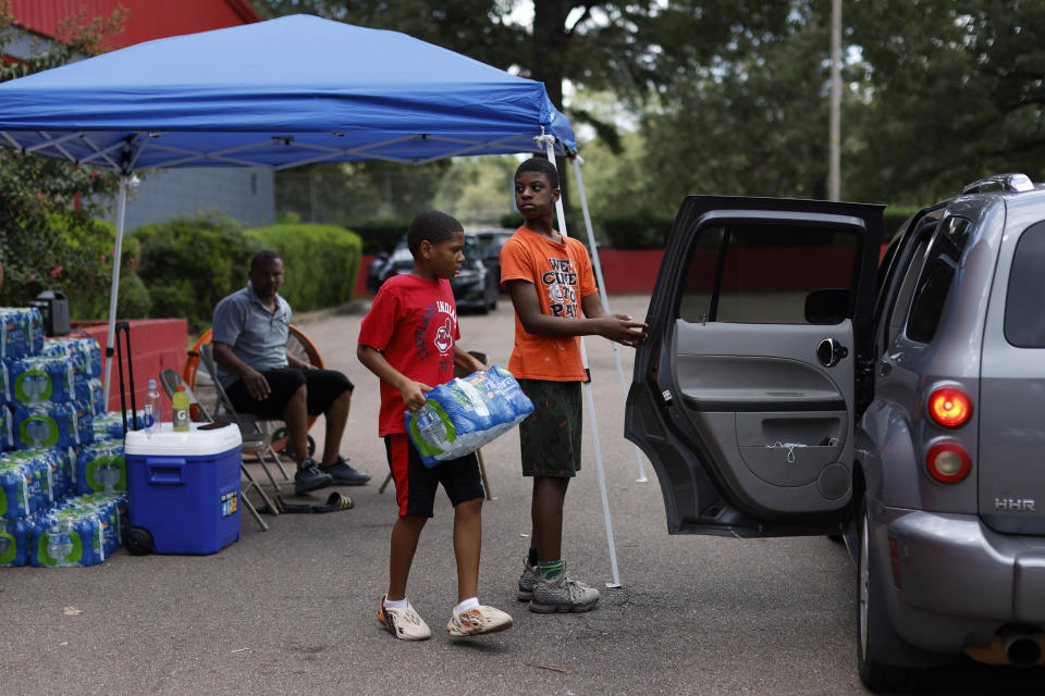 Image: Tyisin Peoples, left, and Joshua Freeman distribute bottled water to local residents at the Sykes Park Community Center in Jackson, Miss. on Aug. 30, 2022. (Edmund Fountain / The New York Times / Redux)