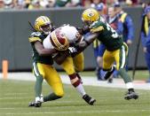 Washington Redskins running back Alfred Morris (C) is tackled by Green Bay Packers safety M.D. Jennings (L) and cornerback Sam Shields during the first half of their NFL football game in Green Bay, Wisconsin September 15, 2013. REUTERS/Darren Hauck