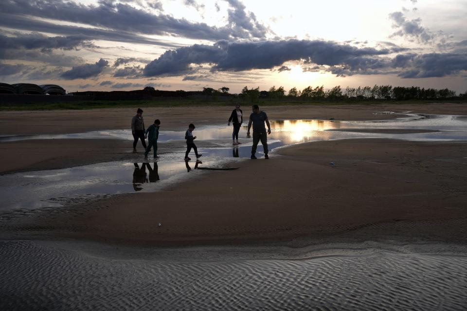 People walk on the exposed bed of a branch of the Paraguay river that has gone dry, in Lambare, Paraguay, Tuesday, Sept. 14, 2021, amid an ongoing drought. (AP Photo/Jorge Saenz)