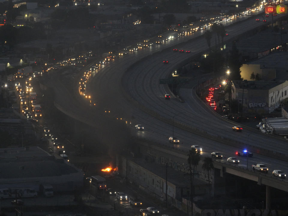 Smoke rises from a small fire as motorists exit through a ramp off Interstate 10, where a section of the freeway is closed due to a recent fire in Los Angeles, Tuesday, Nov. 14, 2023. It will take at least three weeks to repair the freeway damaged in an unrelated arson fire, the California governor said Tuesday, leaving the city already accustomed to soul-crushing traffic without part of a vital artery that serves hundreds of thousands of people daily. (AP Photo/Jae C. Hong)