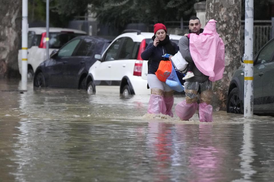 People make their way on a flooded street in Campi di Bisenzio, in the central Italian Tuscany region, Friday, Nov. 3, 2023. Record-breaking rain provoked floods in a vast swath of Tuscany as storm Ciaran pushed into Italy overnight Friday, trapping people in their homes, inundating hospitals and overturning cars. At least three people were killed, and four were missing. (AP Photo/Gregorio Borgia)