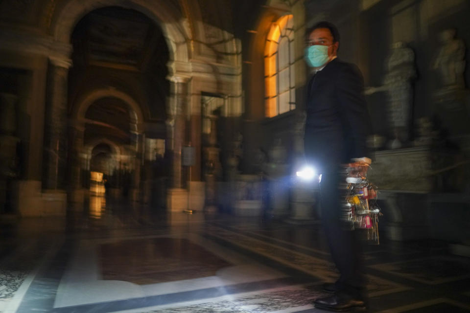 Gianni Crea, the Vatican Museums chief "Clavigero" key-keeper, holds a torch and a bunch of keys as he walks to open the museum's rooms and sections, at the Vatican, Monday, Feb. 1, 2021. Crea is the “clavigero” of the Vatican Museums, the chief key-keeper whose job begins each morning at 5 a.m., opening the doors and turning on the lights through 7 kilometers of one of the world's greatest collections of art and antiquities. The Associated Press followed Crea on his rounds the first day the museum reopened to the public, joining him in the underground “bunker” where the 2,797 keys to the Vatican treasures are kept in wall safes overnight. (AP Photo/Andrew Medichini)
