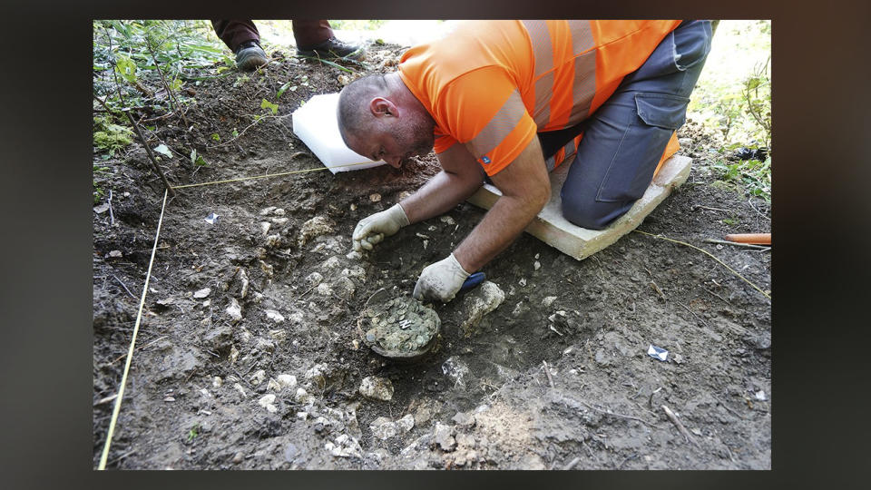 Archaeologists excavate a pot of Roman coins dating to the period of Roman emperor Constantine the Great.