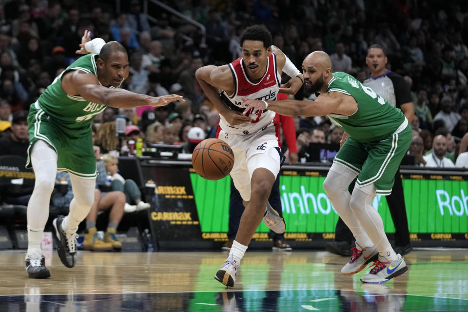 Washington Wizards guard Jordan Poole, center, drives past Boston Celtics center Al Horford, left, and guard Derrick White, right, during the first half of an NBA basketball game Monday, Oct. 30, 2023, in Washington. (AP Photo/Mark Schiefelbein)
