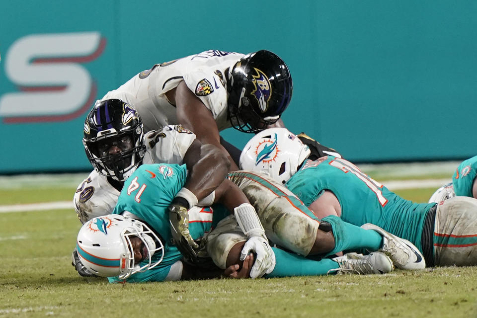 Miami Dolphins quarterback Jacoby Brissett (14) holds his knee after he was sacked by Baltimore Ravens outside linebacker Justin Houston during the second half of an NFL football game, Thursday, Nov. 11, 2021, in Miami Gardens, Fla. (AP Photo/Wilfredo Lee)