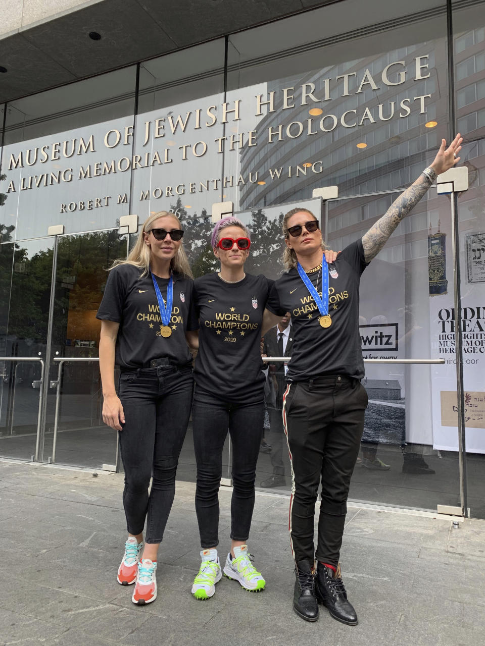 In this Wednesday, July 10, 2019 photo provided by Jeff Simmons, U.S. women's soccer player Ashlyn Harris raises her left arm next to her teammates, Allie Long and Megan Rapinoe, outside the Museum of Jewish Heritage before a victory parade in New York City, to celebrate the team's Women's World Cup title. On Friday, July 19, 2019, The Associated Press reported on stories circulating online incorrectly asserting that Harris is giving a Nazi salute. This photo was made after the museum hosted a breakfast for players before the parade, said Simmons, the executive vice president for Anat Gerstein, Inc., a public relations firm that works with the museum. (Jeff Simmons via AP)