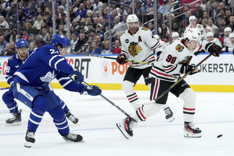 Toronto Maple Leafs left wing Matthew Knies, front left, trips Chicago Blackhawks center Connor Bedard (98) during third-period NHL hockey game action in Toronto, Monday, Oct. 16, 2023. (Nathan Denette/The Canadian Press via AP)