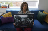 Sakara Remmu, of the Washington Black Lives Matter Alliance, poses for a photo, Sunday, July 25, 2021, in Seattle with a picture from the "March of Silence" that she organized in 2020 that saw thousands of people march silently through the streets of Seattle in protest against police brutality and racial inequality. Washington state is embarking on a massive experiment in police reform and accountability following the racial justice protests that erupted after George Floyd's murder last year, with nearly a dozen new laws that took effect Sunday. Remmu said the new laws are "a mandate from the people to stop cops from violating our rights and killing people." (AP Photo/Ted S. Warren)