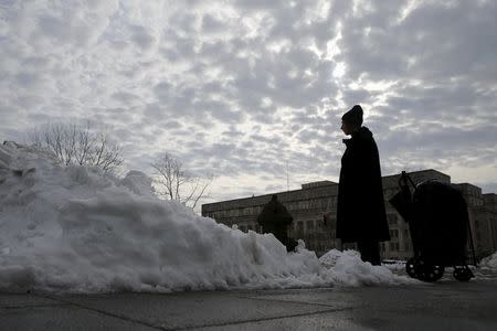 A homeless man stands with his belongings amidst piles of plowed snow on a sidewalk in Washington January 26, 2016. REUTERS/Jonathan Ernst