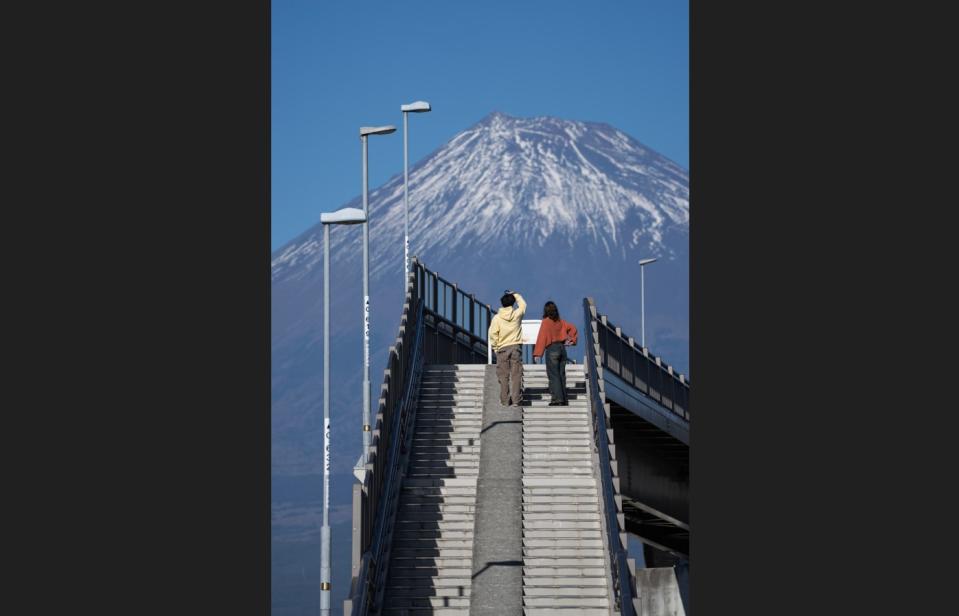 兩名遊客從「富士山夢之大橋」行人天橋的樓梯上眺望富士山。（資料照／Getty Images）