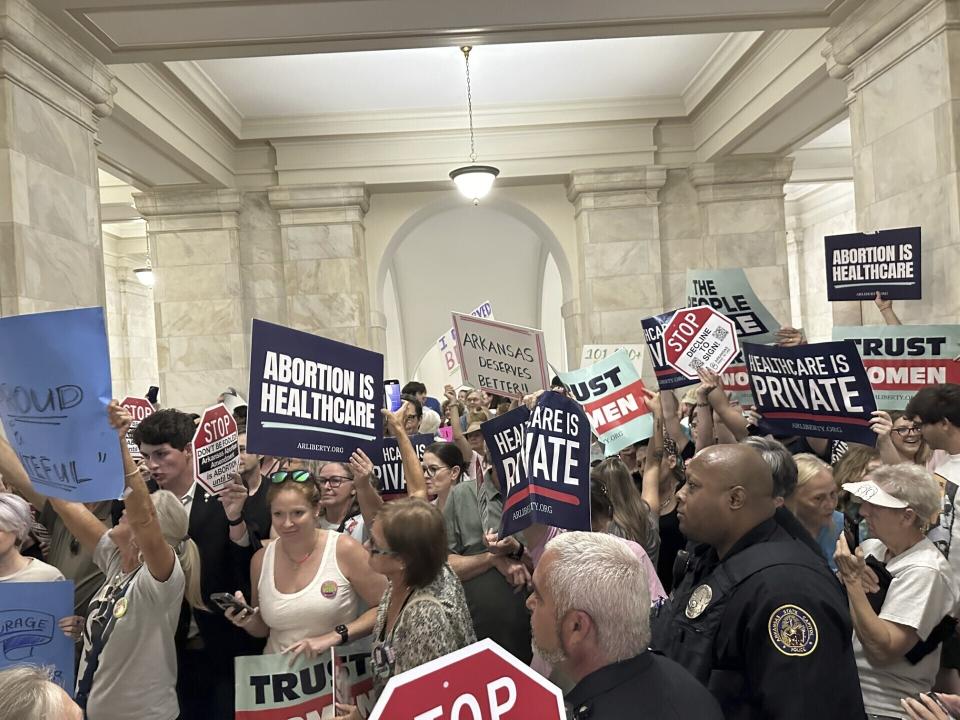 Supporters and opponents of a proposed ballot measure to scale back Arkansas' abortion ban hold signs outside the old Supreme Court chamber at the state Capitol in Little Rock, Ark. Friday, July 5, 2024. Organizers submitted petitions to try and get the proposals on the November ballot. (AP Photo/Andrew DeMillo)