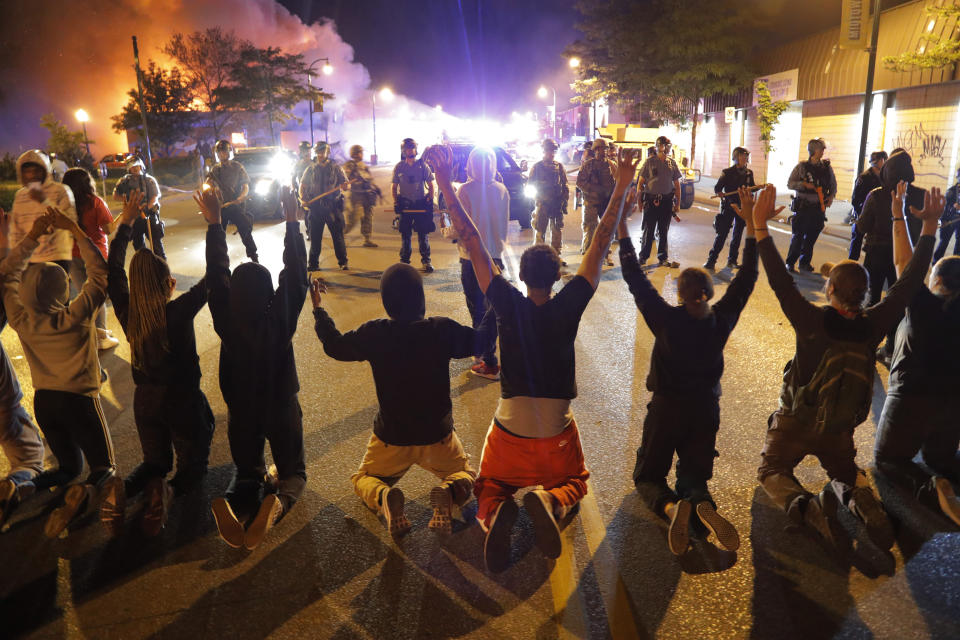 Manifestantes se arrodillan ante policías, el 30 de mayo de 2020, en Minneapolis, durante protestas por la muerte de George Floyd a manos de la policía. (AP Foto/Julio Cortez)