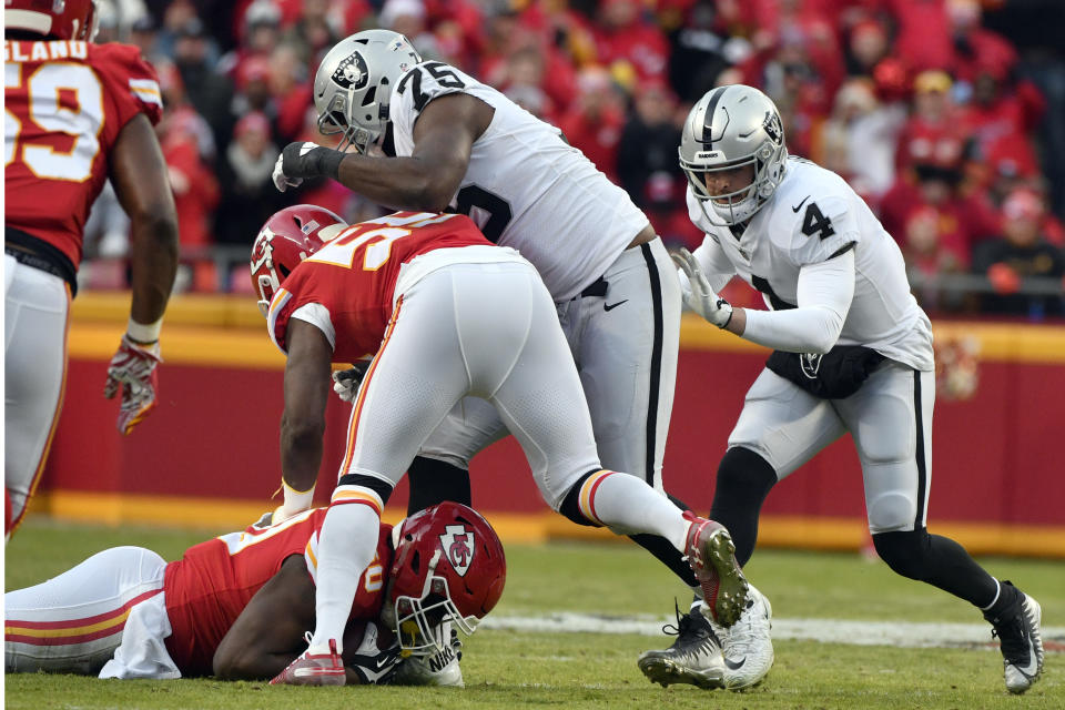 Oakland Raiders offensive tackle Brandon Parker (75) and quarterback Derek Carr (4) stand over Kansas City Chiefs linebacker Justin Houston, bottom left, who recovers a fumble by the Oakland Raiders for a turnover, during the first half of an NFL football game in Kansas City, Mo., Sunday, Dec. 30, 2018. (AP Photo/Ed Zurga)