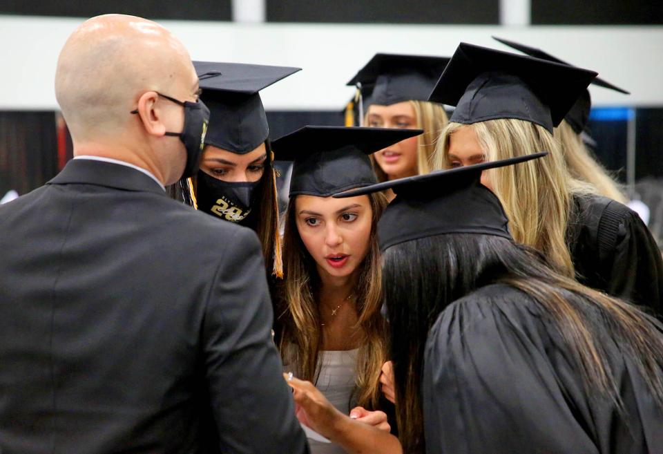 Mylla Ode, center, along with her classmates from Olympic Heights Community High School surround teacher Ricardo Almeida to view their seating assignments for High School Graduation at The South Florida Fairgrounds Wednesday, June 9th, 2021.