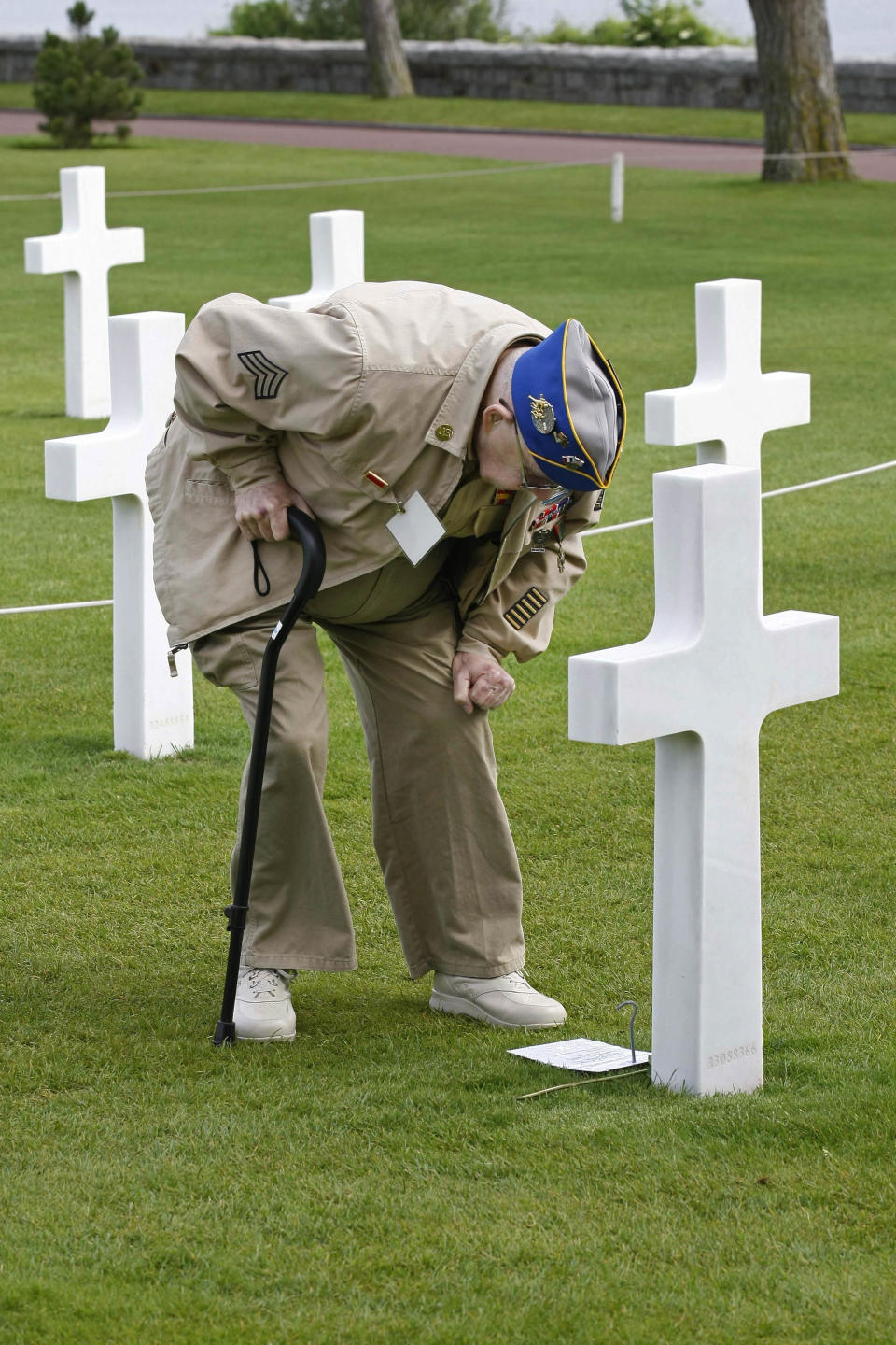 U.S. WW II veteran Clarence Mac Evans, 87, from West Virginia, who landed in Normandy on June 6, 1944, with the 29th infantry division, leans on the tomb of comrade Franck Nuzzo, from the 29th division who died on June 6, 1944, at the Colleville American military cemetery.(AP Photo/Remy de la Mauviniere)