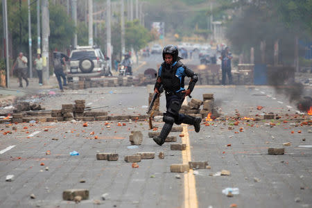 A riot policeman runs toward his colleagues during clashes with university students protesting over a controversial reform to the pension plans of the Nicaraguan Social Security Institute (INSS) in Managua, Nicaragua April 20, 2018. REUTERS/Oswaldo Rivas