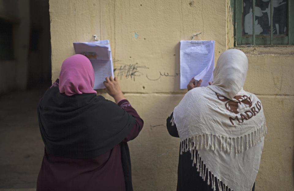 Women search for their names on a polling list before casting their votes in the country's constitutional referendum in Cairo, Egypt, Tuesday, Jan. 14, 2014. Egyptians have started voting on a draft for their country's new constitution that represents a key milestone in a military-backed roadmap put in place after President Mohammed Morsi was overthrown in a popularly backed coup last July. (AP Photo/Khalil Hamra)