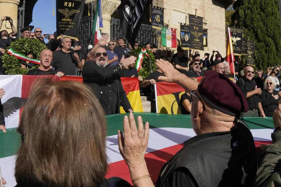 People perform a roman salute in the hometown of former dictator Benito Mussolini to mark the 100th anniversary of the coup d'etat by which he sized power in 1922, in Predappio, Italy, Sunday, Oct. 30, 2022. (AP Photo/Luca Bruno)