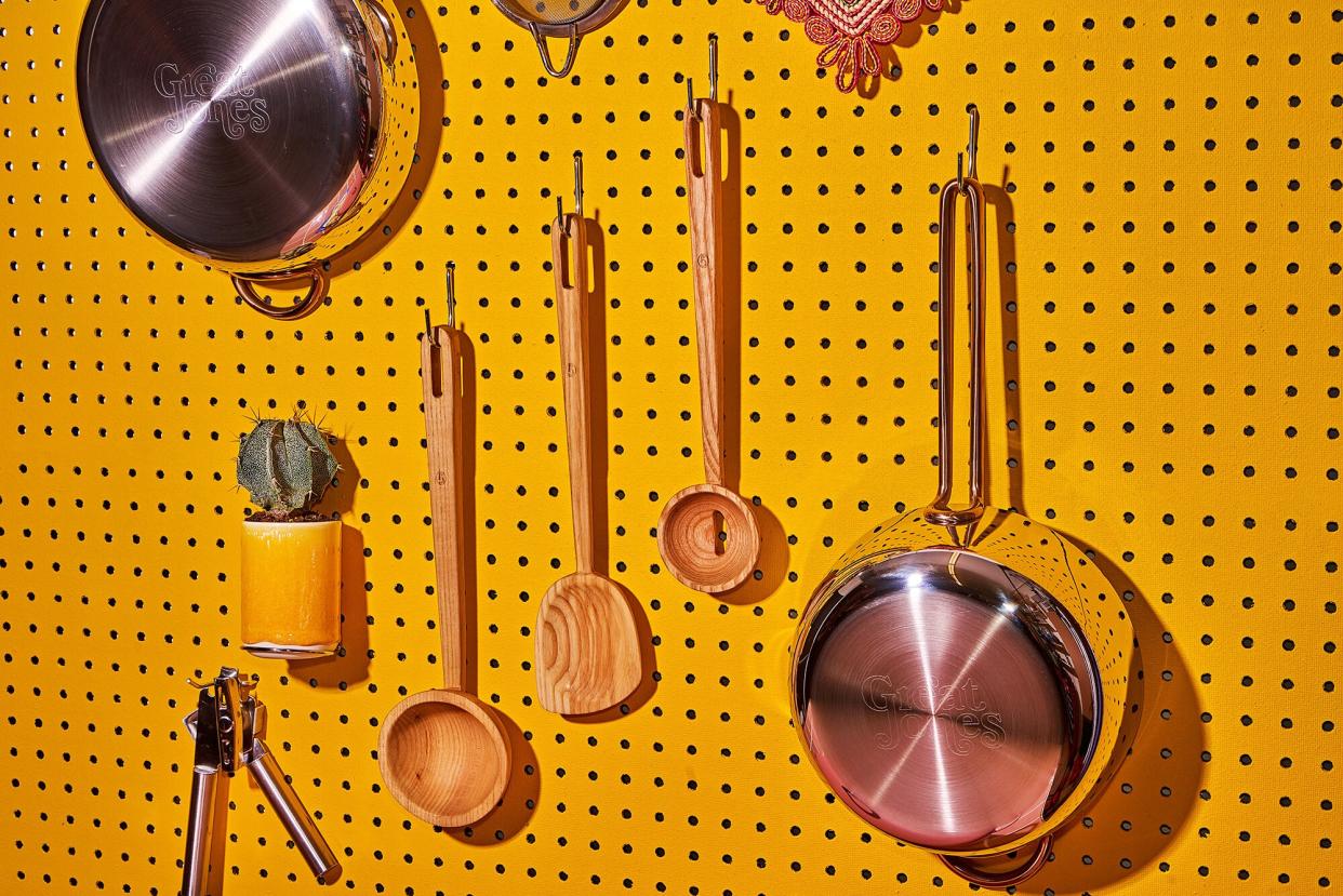 Great Jones products hanging on a yellow peg board with a cactus