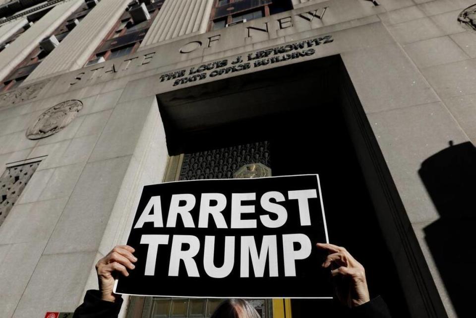 Un manifestante sostiene un cartel frente al edificio de oficinas Louis Lefkowitz del estado de Nueva York, donde se escucha el testimonio del gran jurado en la posible acusación del expresidente Donald Trump, en Nueva York.