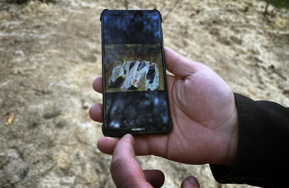 El padre Vasyl Bentsa muestra una foto de cinco individuos que murieron tras ser torturados y baleados, incluido Mykola Moroz, apodado Kolia, en el sitio donde los enterró temporalmente en Zdvyzhivka (Ucrania). (AP Photo/Erika Kinetz)