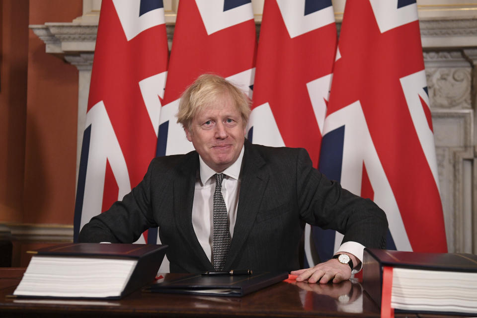 Britain's Prime Minister Boris Johnson signs the EU-UK Trade and Cooperation Agreement at 10 Downing Street, London Wednesday Dec. 30, 2020. The U.K. left the EU almost a year ago, but remained within the bloc’s economic embrace during a transition period that ends at midnight Brussels time —- 11 p.m. in London — on Thursday. European Commission President Ursula von der Leyen and European Council President Charles Michel signed the agreement during a brief ceremony in Brussels on Wednesday morning then the documents were flown by Royal Air Force plane to London for Johnson to add his signature. (Leon Neal/Pool via AP)